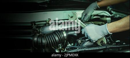 Mechanic works on the engine of the car e in the garage,car repair service. Stock Photo