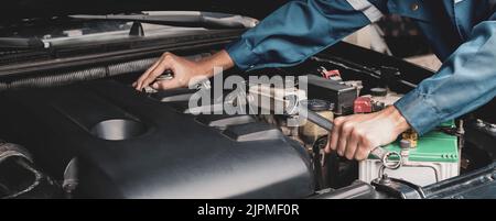Mechanic works on the engine of the car e in the garage,car repair service. Stock Photo