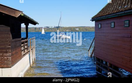 colorful boat houses on lake Ammersee with sailing boats and the Alps in the background in the Bavarian fishing village Schondorf (Bavaria, Germany) Stock Photo