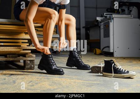 Female legs in carpenter shop, change of footwear tying lace concept Stock Photo