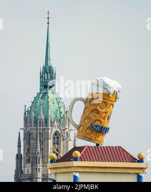 Munich Octoberfest, a large beer mug in Theresienwiese against the backdrop of St. Paul's Gothic church. Munich, GERMANY - August 2022 Stock Photo