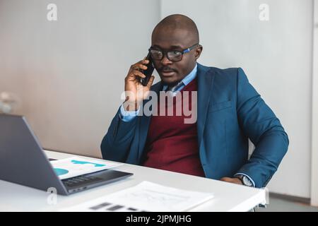 A black African American businessman in a business suit works at a laptop. Self-development and distance learning Stock Photo