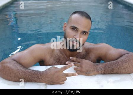 Middle eastern man showing peace sign in swimming pool Stock Photo
