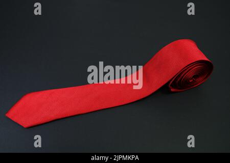 red color polyester fabric necktie rolled on black background with high angle Stock Photo