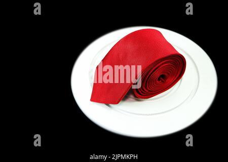 red color polyester fabric necktie rolled isolated on white color display mate with black background Stock Photo