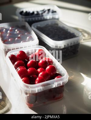 Ripe berries in plastic boxes are ready to be frozen in the freezer. Low Carb Cherry and Honeysuckle are used on the keto diet. Berries are rich in Stock Photo