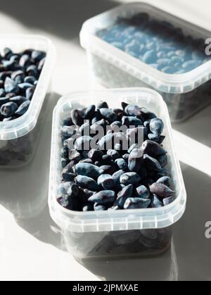 Ripe berries in plastic boxes are ready to be frozen in the freezer. Low Carb Cherry and Honeysuckle are used on the keto diet. Berries are rich in Stock Photo