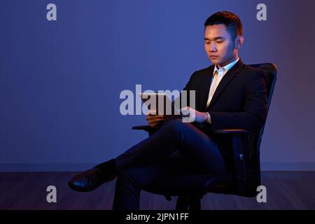 Young confident entrepreneur reading information on tablet computer Stock Photo