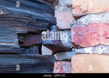 An old rusty hinge between an old brick wall Stock Photo