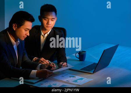Young Asian business people discussing documents at meeting Stock Photo