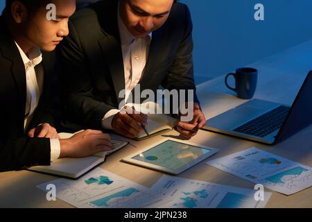 Business people working with charts and diagrams late at night Stock Photo