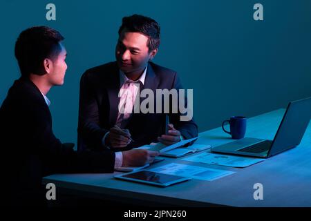 Asian business executives having meeting in dark office Stock Photo