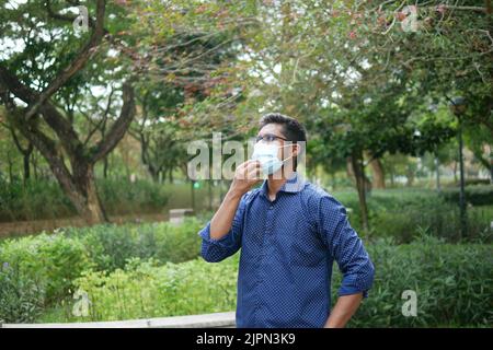 young asian man taking mask off outdoor  Stock Photo