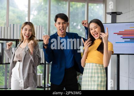 Group of Asia young entrepreneurs creative people looking at camera and excited for success project, working together in the office. Stratup business Stock Photo