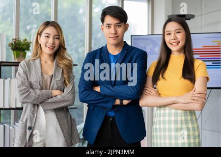 Group of Asia young entrepreneurs creative people looking at camera and smiling after brainstorming, working together in the office. Stratup business Stock Photo