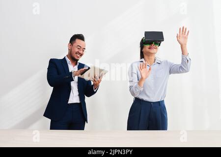 Group of Asian developers gathered together at modern office and testing virtual reality headset, white background Stock Photo
