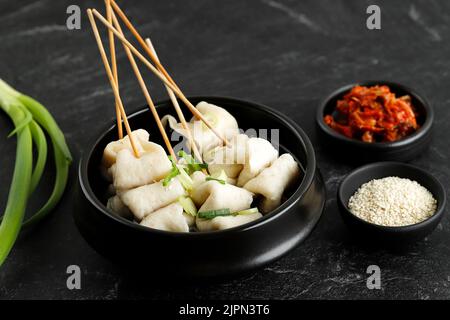 https://l450v.alamy.com/450v/2jpn3t6/korean-odeng-tangeomuk-odeng-guk-korean-fish-cake-soup-in-traditional-pot-on-black-table-background-served-with-kimchi-2jpn3t6.jpg