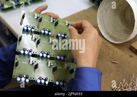 A man collects a printed circuit board. The worker solders the radio components and assembles the finished device. Manual assembly and control Stock Photo