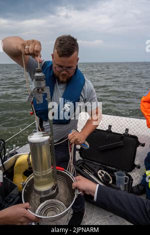 19 August 2022, Mecklenburg-Western Pomerania, Ueckermünde: An employee of the State Agency for Agriculture and Environment Western Pomerania (StALU VP) takes further water samples from the Szczecin Lagoon in Ueckermünde. So far, according to official information, no fish carcasses have been discovered in the German part of the lagoon in connection with the Oder fish kill. Nevertheless, as a precautionary measure, authorities advise against bathing, fishing and taking water from the Szczecin Lagoon. Tourism businesses have already reported a drop in visitors. The German-Polish border river Ode Stock Photo