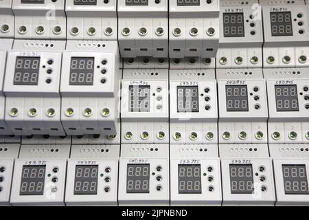 Service center for the repair of power voltage relays. Human checking electrical device with digital display. Numbers on the test bench. Manufacture o Stock Photo