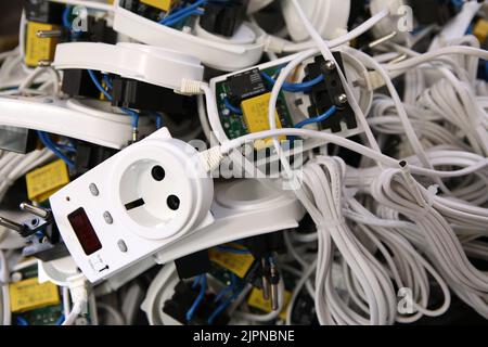 Service center for the repair of power voltage relays. Human checking electrical device with digital display. Numbers on the test bench. Manufacture o Stock Photo