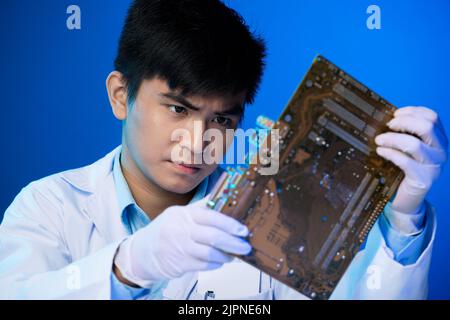 Professional Asian electronic engineer looking at big circuit board in his hands Stock Photo