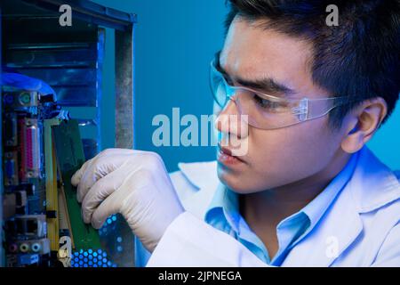 Computer technician putting board into hard drive Stock Photo