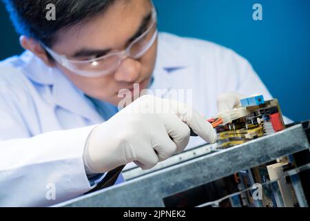 Asian electronic engineer checking wires of robot he created Stock Photo
