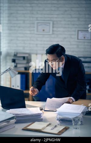 Vietnamese professional lawyer reading document on laptop screen Stock Photo
