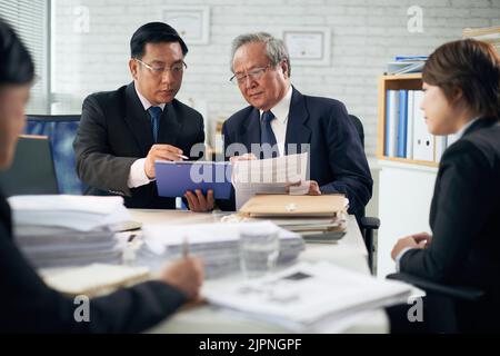 Professional Vietnamese lawyer consulting his coworker Stock Photo