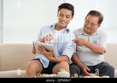 Senior man and his grandson watching something on tablet computer Stock Photo