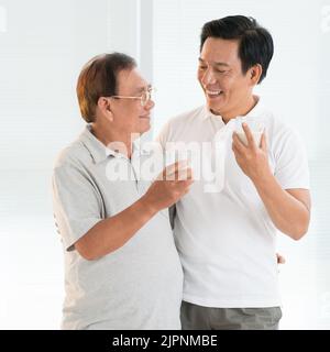 Happy senior man and his adult son drinking milk Stock Photo