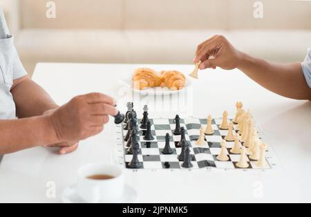 Teenager and his grandfather playing chess together Stock Photo