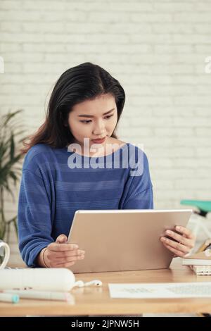 Young Vietnamese business executive watching presentation on tablet computer Stock Photo