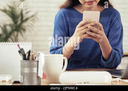 Cropped image of young woman using application on her phone Stock Photo