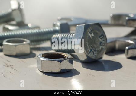 Bolts and nuts are scattered on a wooden surface close-up. Construction Stock Photo