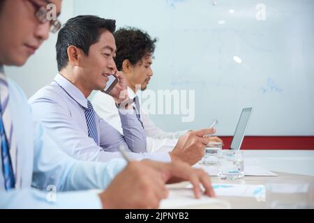 Cheerful Asian business executive consulting client on the phone Stock Photo