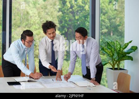 Asian entrepreneurs working with documents during meeting Stock Photo