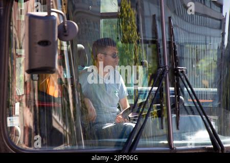 Belgrade-Serbia - June 15, 2022: Driver driving a city bus, from outside through front windscreen with reflections on glass Stock Photo