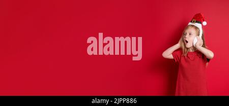 Long banner. girl in christmas clothes, surprise and laugh on a red background Stock Photo