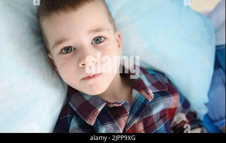 Portrait of cute little boy in colored shirt looking at camera with serious attentive face Stock Photo