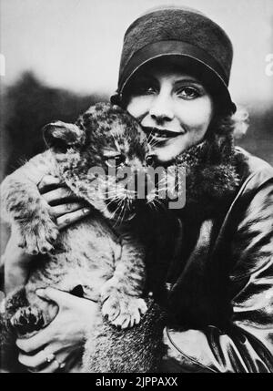 1925 ca. , USA  : The  movie actress  GRETA GARBO ( 1905 - 1990 ) with a little lion , the symbol of Metro Goldwyn Mayer in a pubblicity Studios still  - MOVIE - CINEMA - portrait - ritratto  - smile - sorriso  - hat - cappello - cloche - pelliccia  - fur - cucciolo di leone - felino - personalità celebrità attori con animale animali - personality personalities celebrity celebrities with animals  ----  Archivio GBB Stock Photo