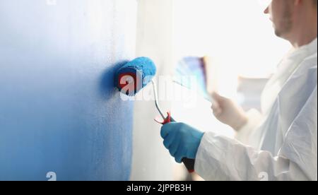 Painting white wall with blue roller closeup Stock Photo