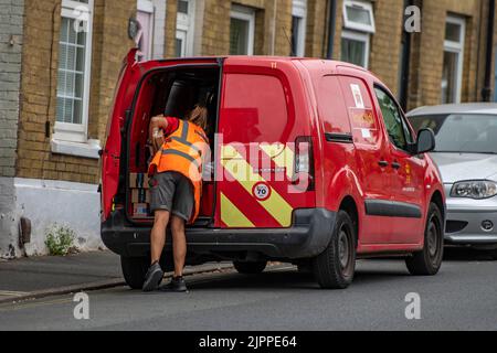 female post office worker getting letters and parcels from the back of a red royal mail van on a delivery round in cowes on the isle of wight. postie. Stock Photo
