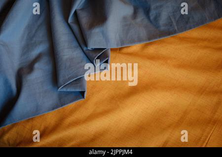 Bicolor background gray orange fabric, crumpled fabric folds, selective focus Stock Photo