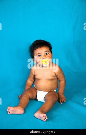 Native American baby, from the Santa Clara Pueblo, wearing a diaper sucks on a pacifier. Stock Photo