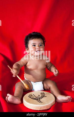 Native American baby, from the Santa Clara Pueblo in New Mexico,  plays a traditional hand drum. Stock Photo