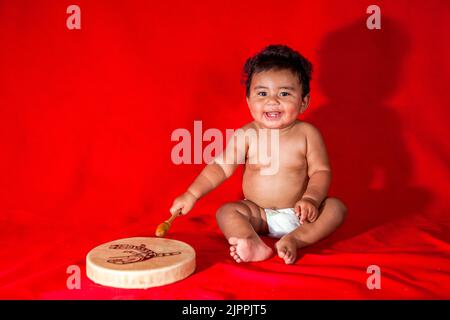 Native American baby, from the Santa Clara Pueblo in New Mexico,  plays a traditional hand drum. Stock Photo