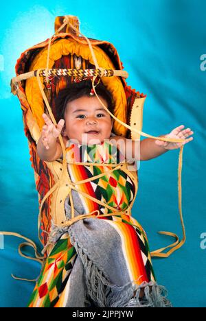 Happy Native American Baby, from the Santa Clara Pueblo of New Mexico, in traditional cradleboard, Stock Photo