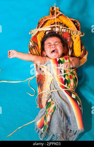 Crying Native American Baby, from the Santa Clara Pueblo of New Mexico, in traditional cradleboard, Stock Photo